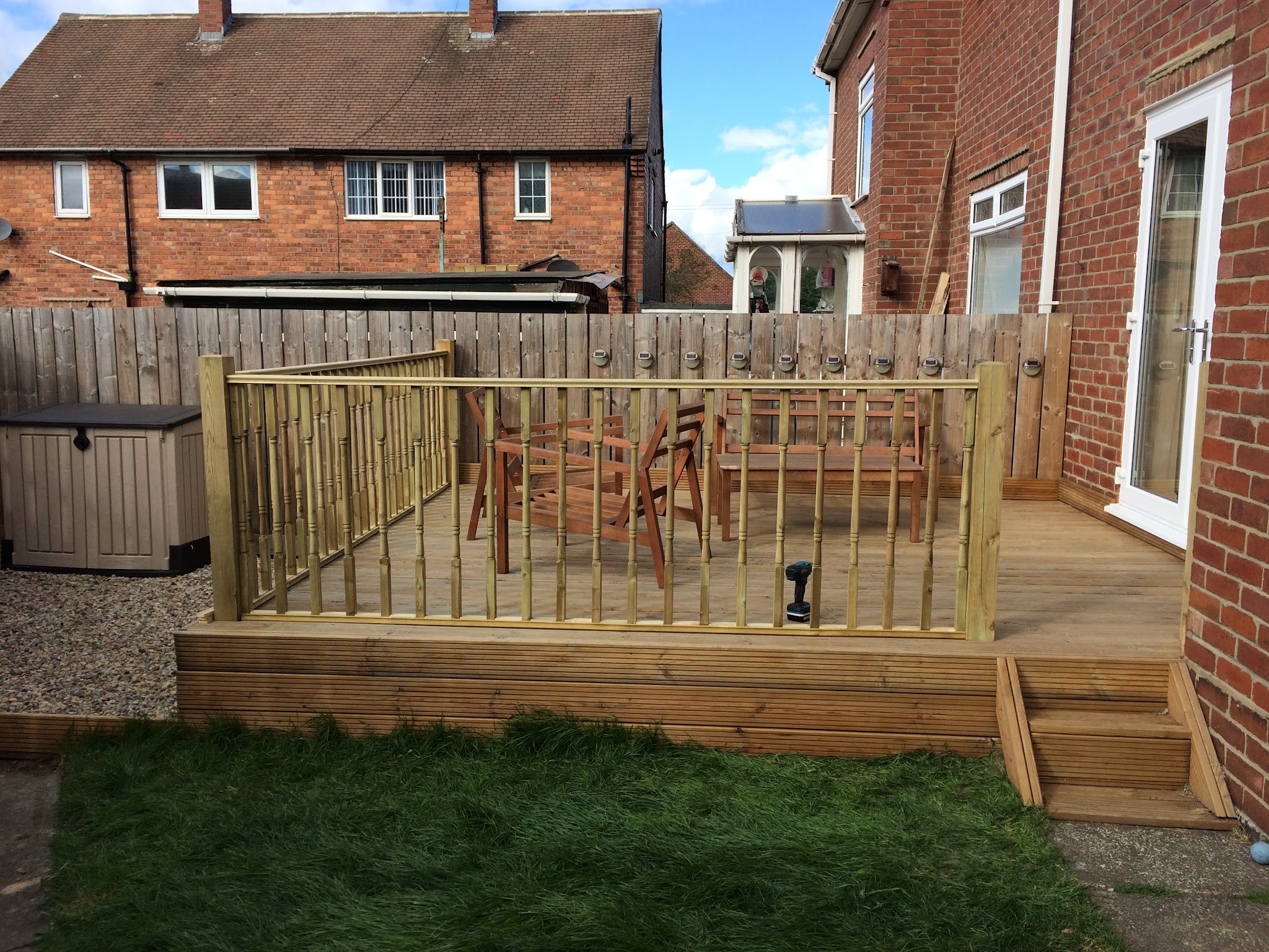 Raised timber decking with spindle balustrade and steps, built beside a brick house