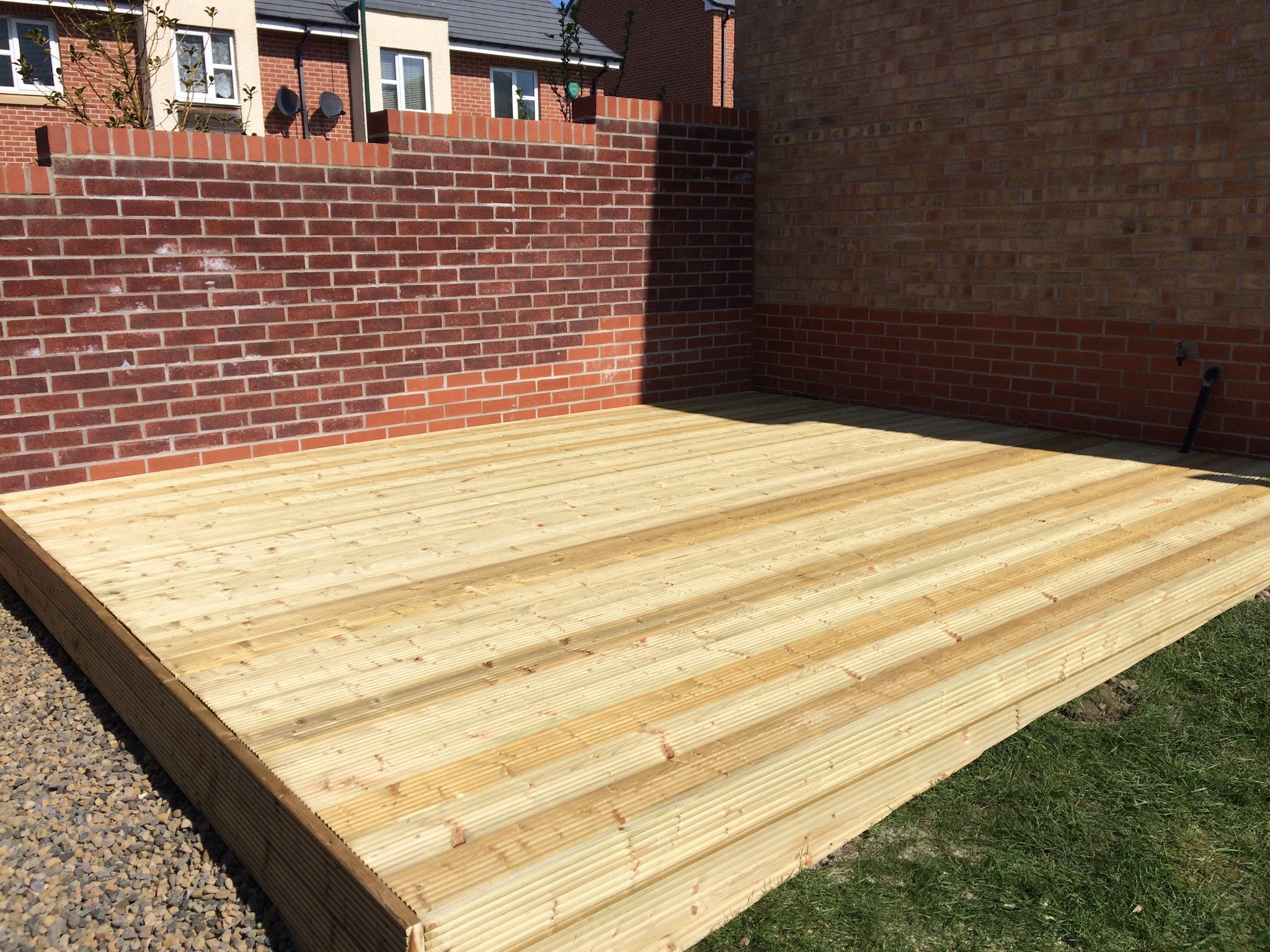 A large new timber deck laid across a walled back garden